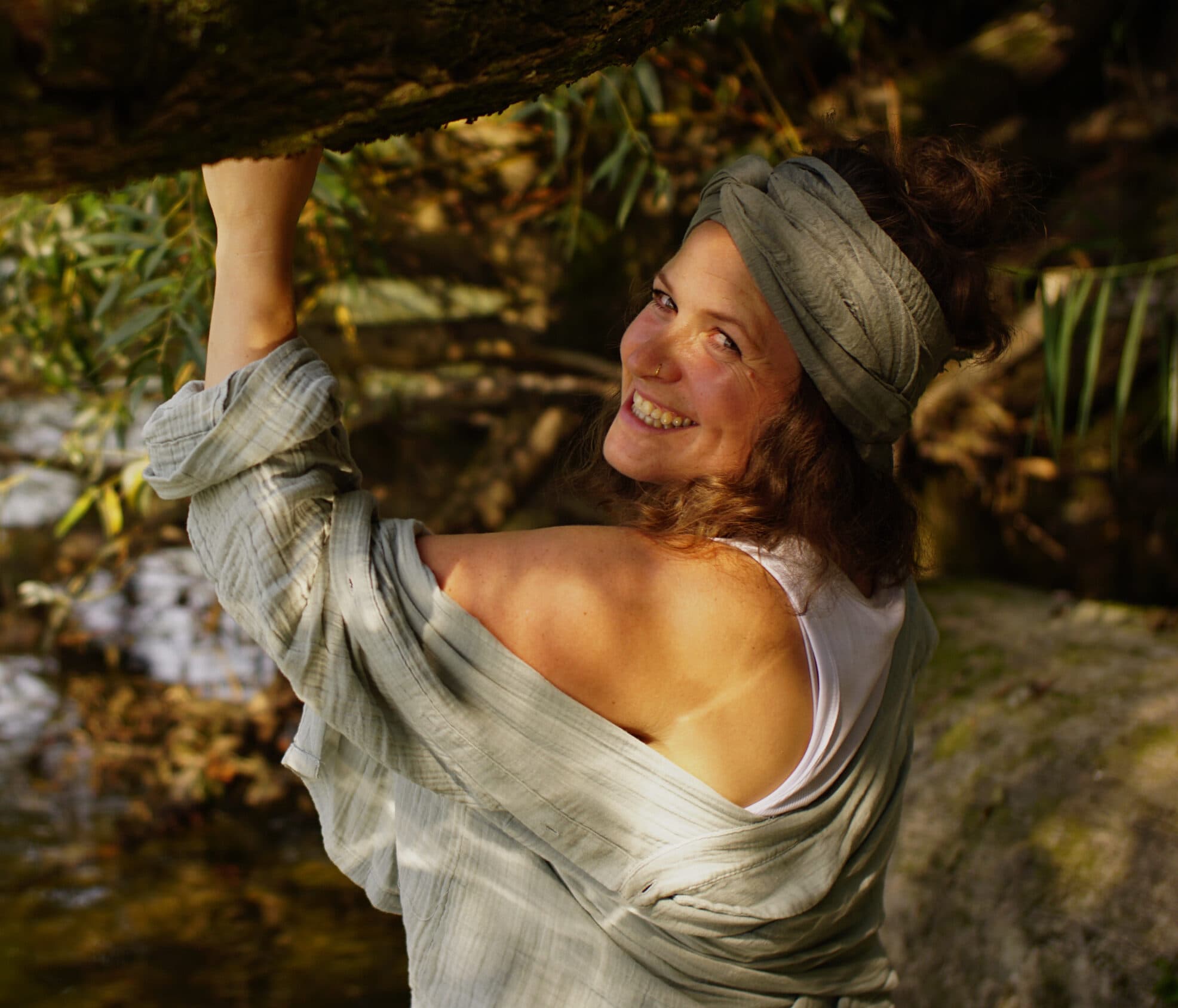 Miriam Faber lächelt über die Schulter, hinter ihr Weidenzweige am Fluss